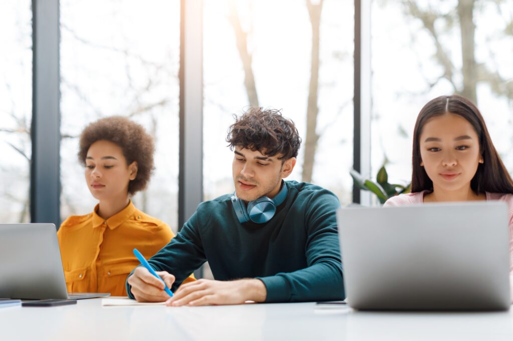 Diverse students focused on their tasks with laptops and notes